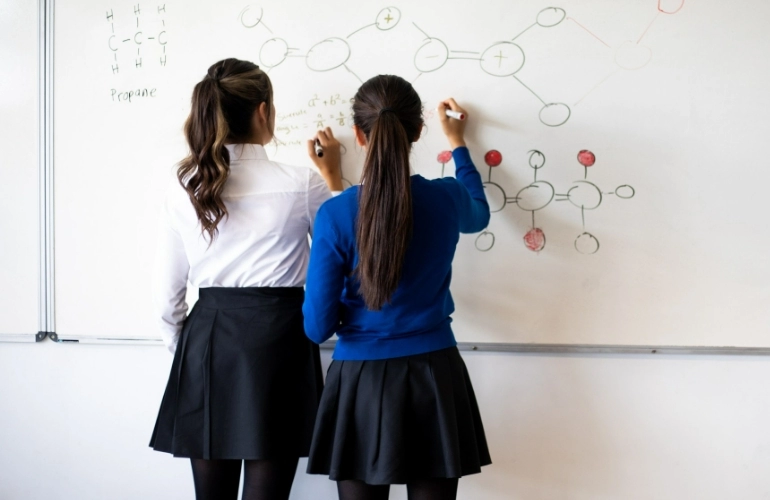 Dziewczyny piszące wzory chemiczne na tablicy